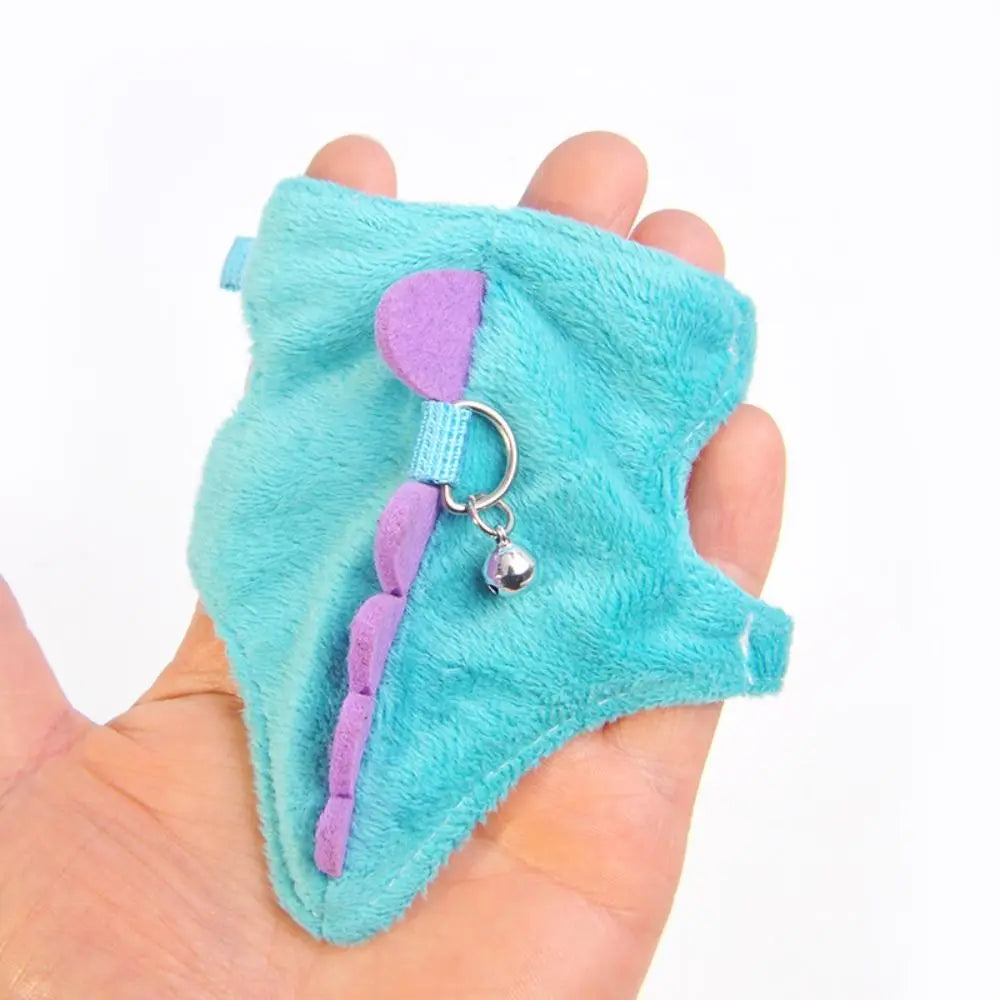 A turquoise felt vest harness with a purple strap and silver charm is held in a hand.