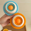 Eine Hand hält ein orange interaktives Tier-Lickspielzeug mit konzentrischen Ringen, das Emotionen beruhigt.