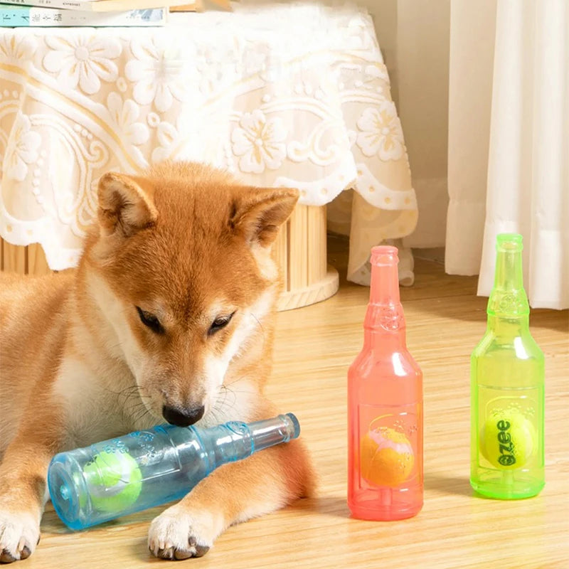 A small dog lies next to three glass bottles containing green, orange, and yellow liquid toys.