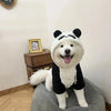 A white and black panda-themed fleece dog coat is sitting on a gray fabric object.