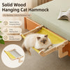 A fluffy gray cat is relaxing in a solid wood hanging cat hammock designed for bedside, sofa, or window use.