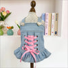 A denim princess style jacket for dogs with pink ribbon details displayed on a wooden hanger.
