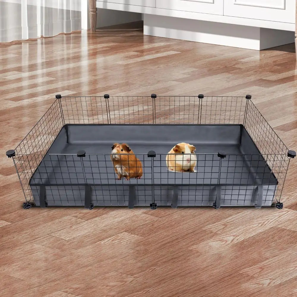 Une cage pour animaux en grillage rectangulaire avec un revêtement gris foncé, posée sur un plancher en bois.
