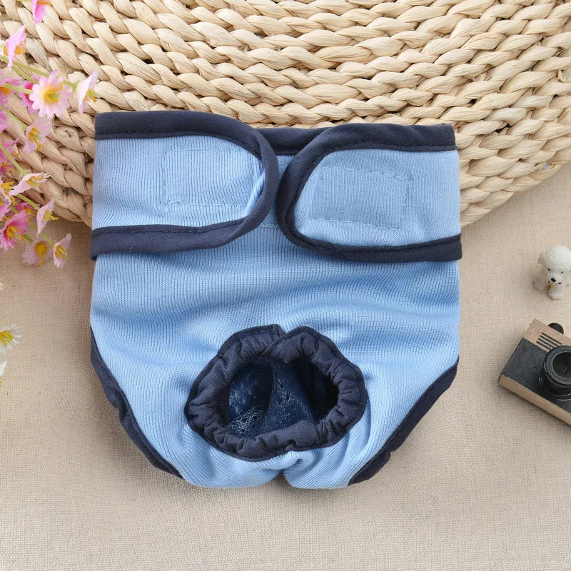 Light blue reusable dog diapers with dark gray trim resting on a woven mat.