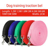 A variety of red, green, blue, and black nylon dog training traction belts with metal clasps are displayed.