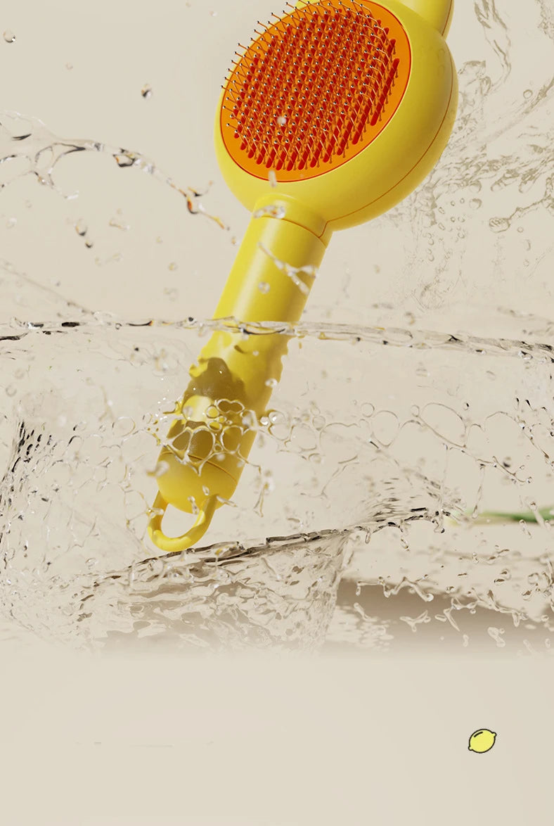 A yellow pet deshedding brush is shown submerged in water, with its orange bristles visible.