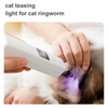 A hand holds a white light device near a dog's ear, illuminating the area with purple light for cat teasing.