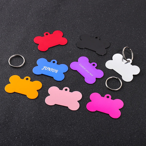 A collection of colorful bone-shaped dog ID tags in various colors including red, black, blue, purple, pink, and orange, with