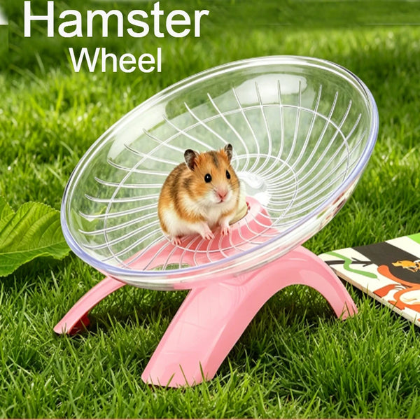 A small brown hamster is running inside a clear plastic wheel on a pink stand outdoors.