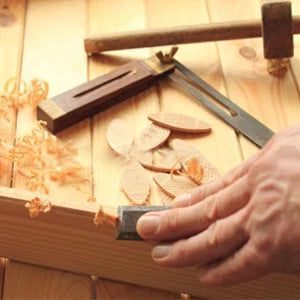 Eine Hand justiert ein verstellbares Holzgatter für den Indoor-Einsatz auf einer Holzoberfläche.