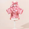 Pijamas de perro de satén rosa con una diadema de lazo a juego, mostrados en un maniquí.