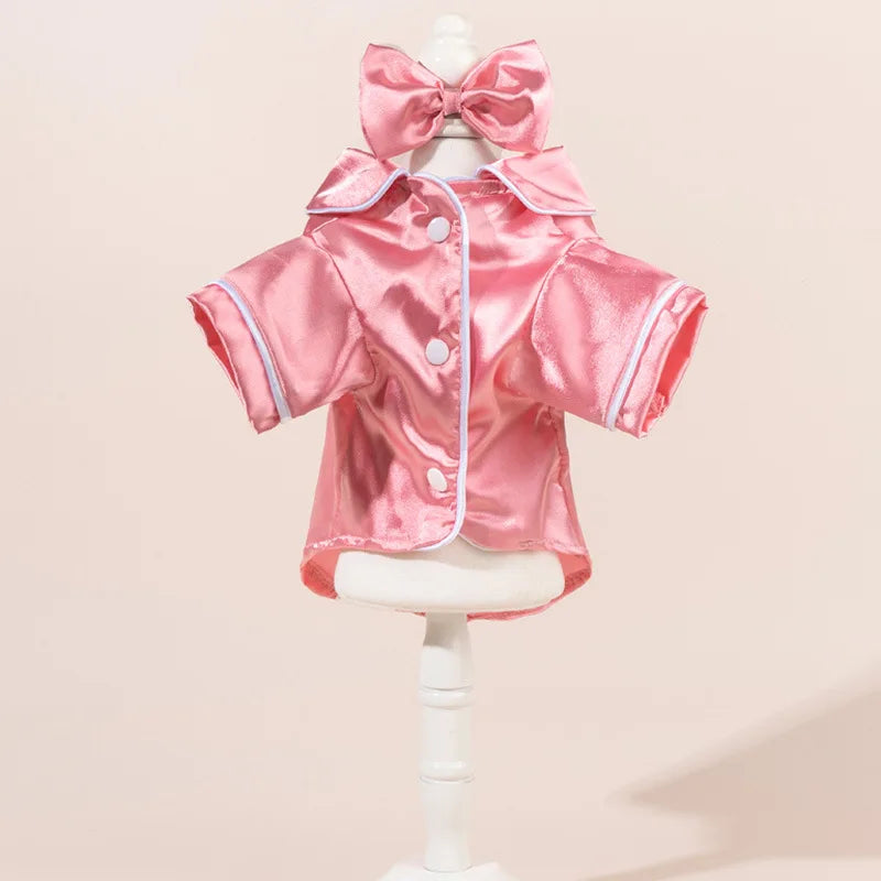 Pijamas de perro de satén rosa con una diadema de lazo a juego, mostrados en un maniquí.