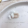 Pink bow hair accessory featuring pearl accents and rhinestones on a white background.