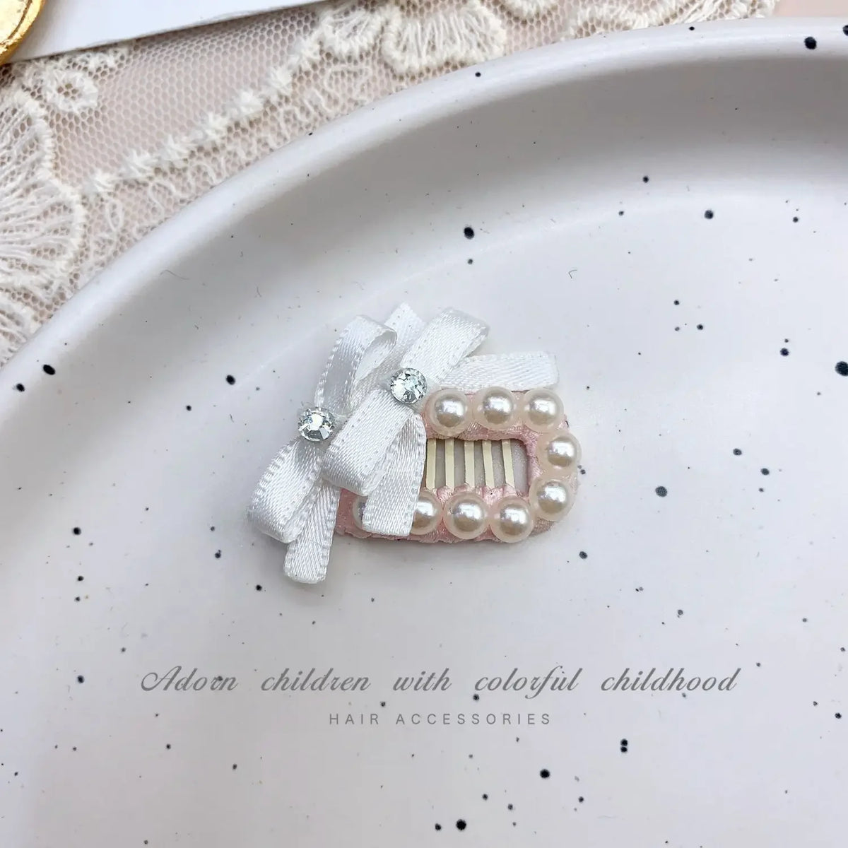 Pink bow hair accessory featuring pearl accents and rhinestones on a white background.