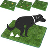 A black dog is standing on a green artificial grass training mat with white clouds drawn on it.