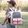 A woman is wearing a pink and white ventilated cat carrier backpack while standing outdoors.