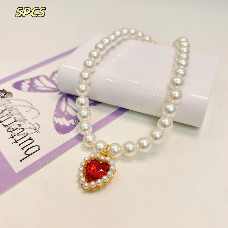 A delicate pearl necklace with a heart-shaped pendant is displayed on a white background.