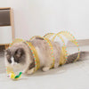 A fluffy gray cat is playing with a yellow and green foldable hunting tunnel for indoor play.