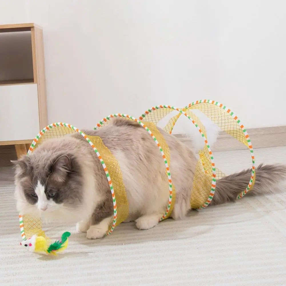 A fluffy gray cat is playing with a yellow and green foldable hunting tunnel for indoor play.