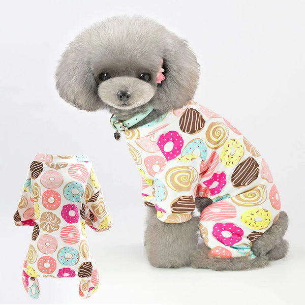 A fluffy gray dog wearing a patterned onesie with colorful dots and shapes.