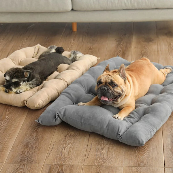 An English bulldog rests on a gray plush pet sofa bed on a wooden floor.