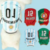 A white dog wearing a sports jersey featuring blue and white stripes, red and green patches, and black lettering.