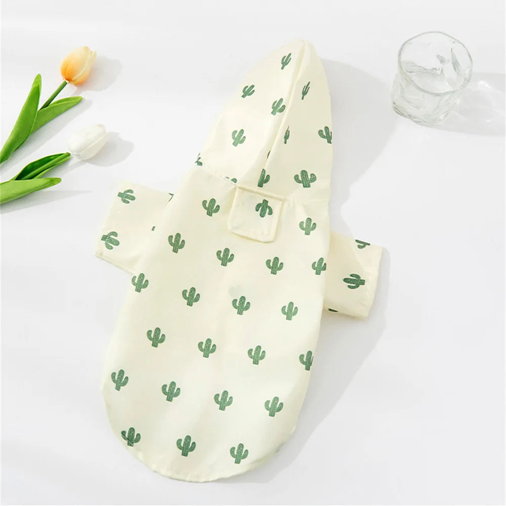 A light cream cartoon printed dog raincoat featuring green cactus patterns, displayed on a white surface.