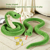 A green snake-shaped toy with an anake-appearance is shown coiled and stretched on a light fabric surface.