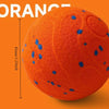 An orange, textured pet ball with blue dots is shown against an orange background.