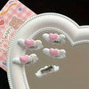 A white heart-shaped tray holds several small white clips with pink hearts and silver clasps.