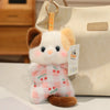 A cute cartoon animal bean bag plush toy resembling a white cat with brown ears and a pink checkered body, displayed next to 