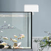 Distributeur automatique de nourriture pour animaux aquatiques, avec lampe blanche et mécanisme d'alimentation.