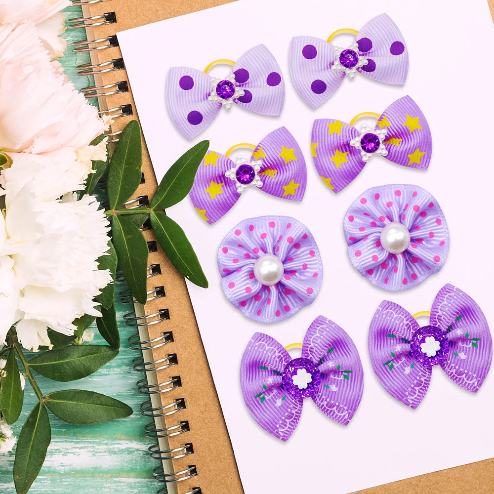 Eine Sammlung lila und violette Hundehairbänder mit Glitzerakzenten auf weißem Papier.