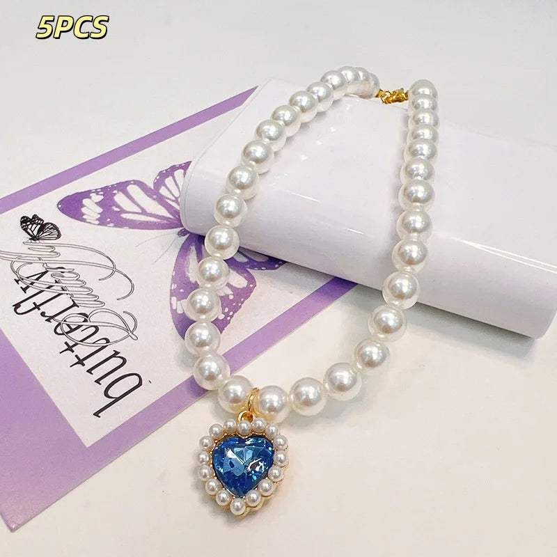 A five-piece necklace featuring a strand of white pearls and a heart-shaped blue gemstone pendant.