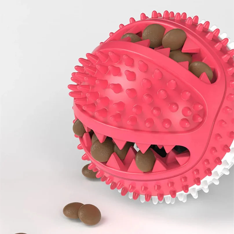 A pink interactive suction cup tug dog ball filled with brown dog treats and teeth-like plastic elements.