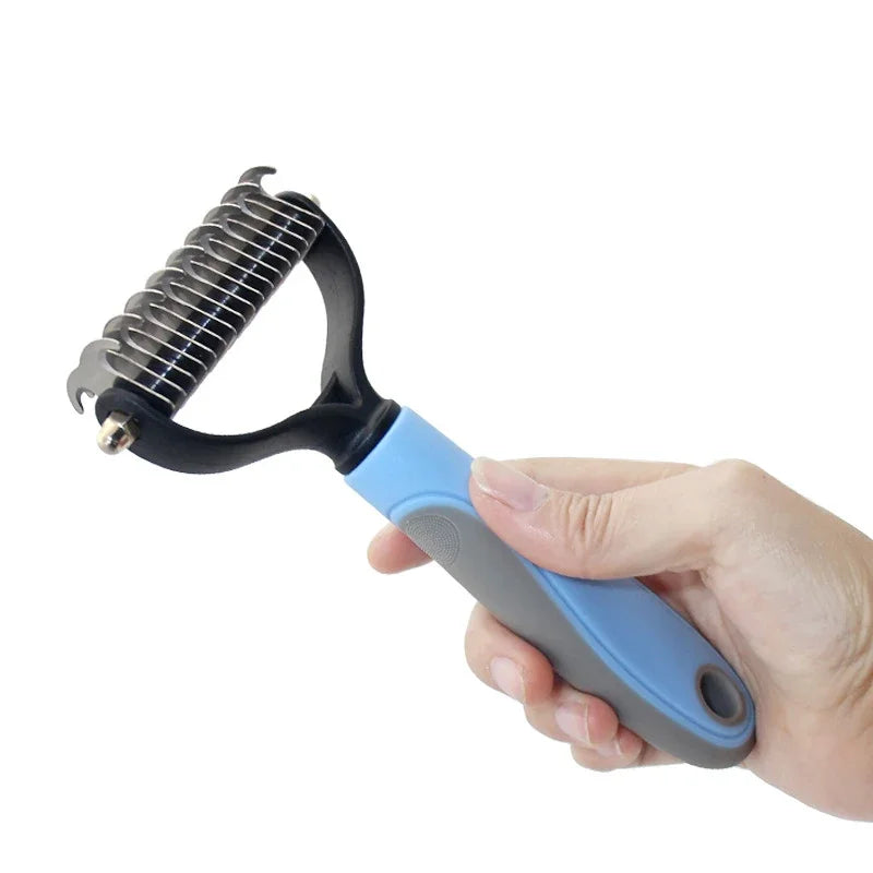 Eine Hand hält eine blaue und graue Tierhaar-Entwirrbürste mit einer Metallbürste.