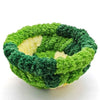 A spherical bird hanging hammock made of green and dark green moss or plant material.