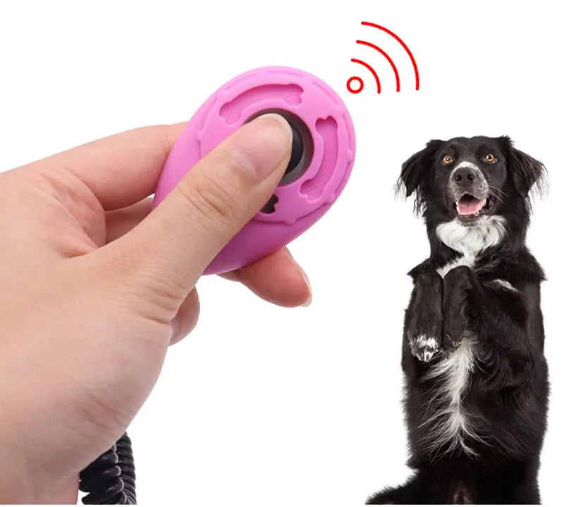 Pinker, verstellbarer Hundetrainer-Klicker wird von einer Hand gehalten, mit einem Hund im Hintergrund.