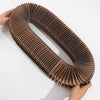 A brown foldable accordion cat scratcher with ridges is being held by a hand.