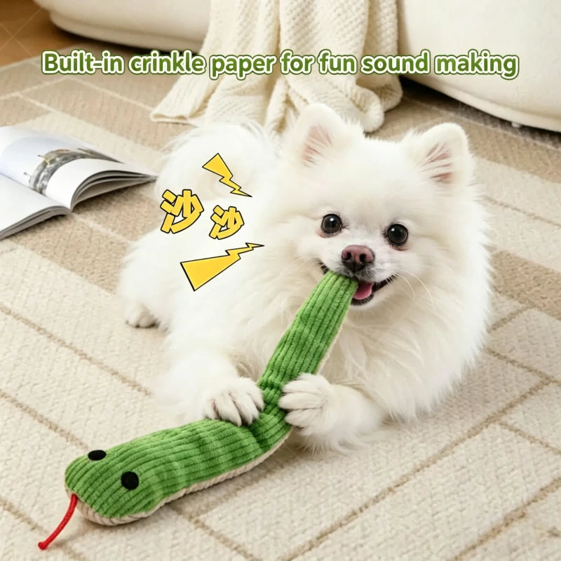 A white fluffy dog is playing with a green crinkle paper snake toy.