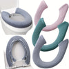 Various plush non-slip toilet seat covers in gray and pink colors shown on a toilet bowl.