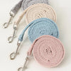 A stack of pet leash harnesses in various neutral tones including gray, beige, and light blue.