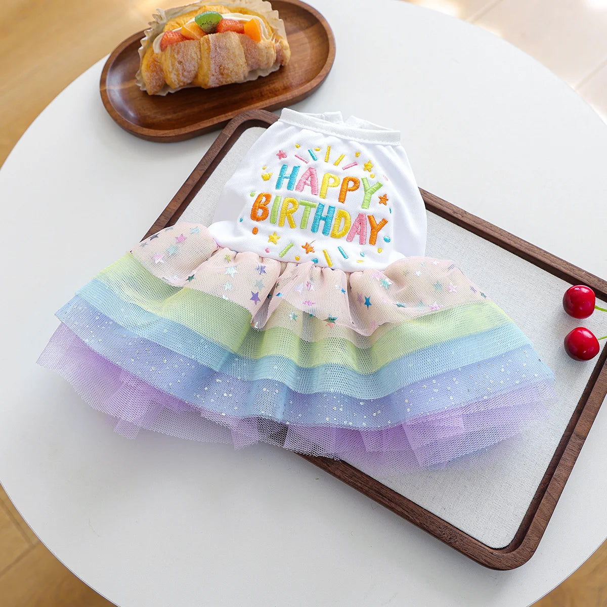 A white tulle birthday outfit for a dog with colorful layers and a happy birthday design