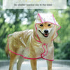 Un chien de couleur beige clair portant un imperméable transparent avec des bordures roses, debout sous la pluie.