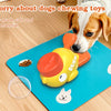 A yellow and orange interactive treat dispenser toy for dogs placed on a blue mat next to a dog.
