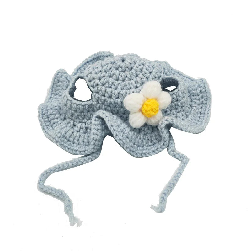 A light blue knitted pet hat shaped like a flower with dangling strings for cats and dogs