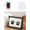 A wooden photo frame displaying two black paw prints on a light background.