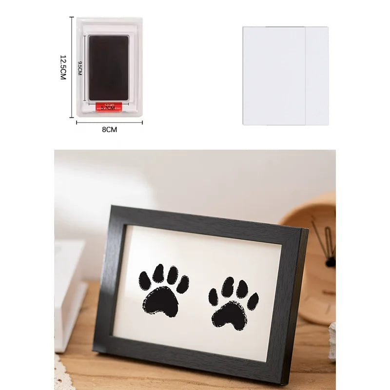 A wooden photo frame displaying two black paw prints on a light background.