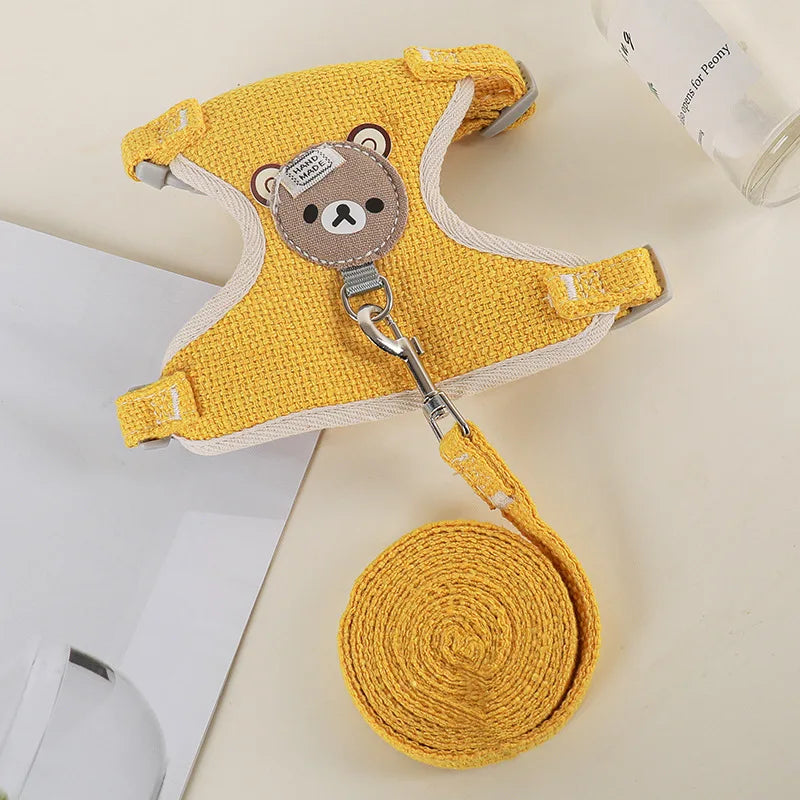 A yellow padded rabbit harness and leash set with a bear charm and coiled yellow fabric.