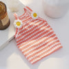 A pink and white polka dot dog vest with daisy appliqués lying on a white surface.